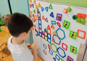 chłopiec układa kompazycje z klocków magnetycznych na tablicy